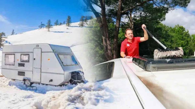 Caravane en hiver sur un terrain enneigé et entretien du toit avec une brosse.