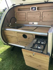 Mini-caravane Tip Top cuisine accessible par l’arrière avec évier, feux à gaz, réfrigérateur et placards