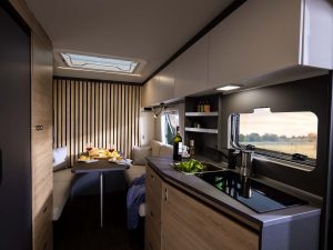  Coin cuisine moderne et espace repas convivial dans la caravane électrique Knaus YASEO 500 DK, avec vue panoramique sur la nature.