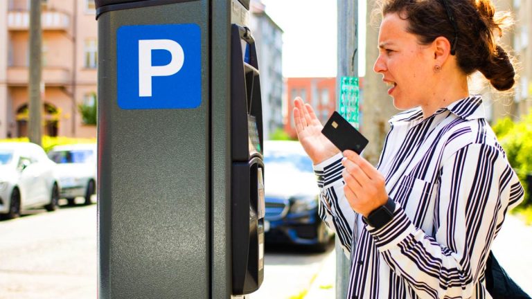 Danger arnaque QR code horodateur : une automobiliste s'apprête à scanner un code suspect sur une borne de parking