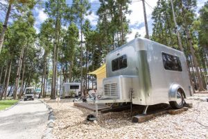 Mini caravane japonaise X-Cabin 300 en aluminium dans un environnement de camping en pleine nature