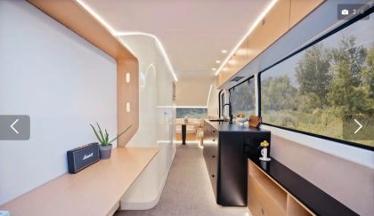 Intérieur moderne d'une caravane Pebble avec cuisine design, coin repas panoramique et éclairage LED intégré, vue sur la nature.