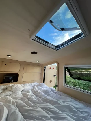 Aménagement intérieur d’une mini-caravane teardrop MyBeelib, avec lit double confortable et finitions bois, idéal pour le camping nomade