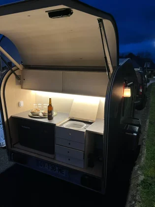 Vue de la cuisine extérieure d’une mini-caravane teardrop MyBeelib, avec rangements intégrés, plan de travail et finitions bois artisanales