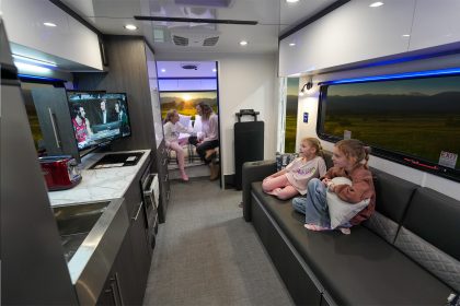 Espace salon de la caravane Aucta Sycamore signé inTech, avec canapé confortable, grande luminosité naturelle et table escamotable, parfait pour le camping haut de gamme et le télétravail nomade.