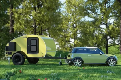 Mini caravane teardrop verte tractée par une Mini Cooper dans un cadre naturel, idéale pour le camping léger et les escapades en pleine nature.