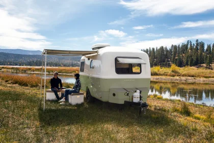 Mini-caravane rétro Happier Camper avec hayon arrière ouvert, design compact en fibre de verre, aux lignes arrondies et finition bicolore.